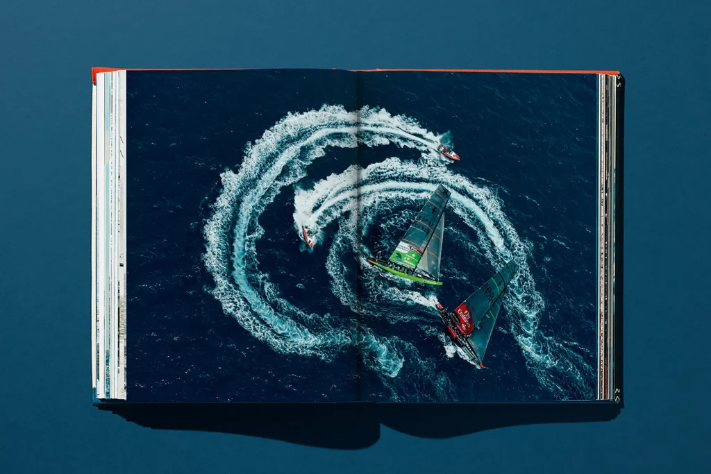 Vue aérienne de deux voiliers de course high-tech de l’America’s Cup entourés de bateaux à moteur laissant des sillages