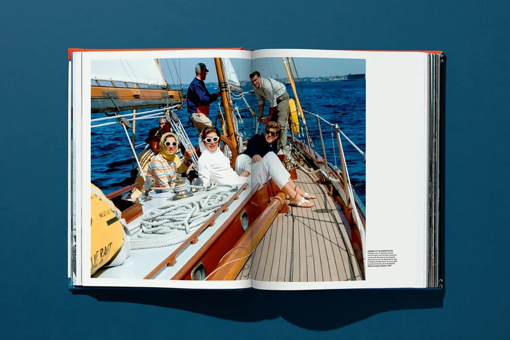 Photo vintage d’hommes et de femmes élégamment habillés se relaxant sur un voilier en bois pendant l’America’s Cup